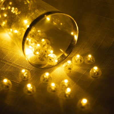 Glowing yellow fairy lights spilling from a glass container.