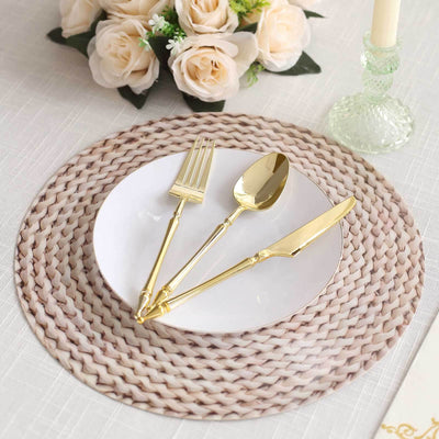 Elegant gold cutlery set on a woven placemat with a white plate and floral arrangement.