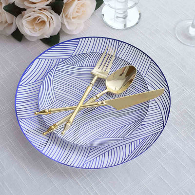 Elegant blue patterned plate with gold cutlery arranged on a textured tablecloth.