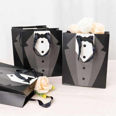 Tuxedo gift bags with black handles and floral accents.