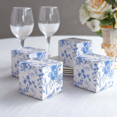 Decorative floral gift boxes on a table with elegant glassware and flowers.