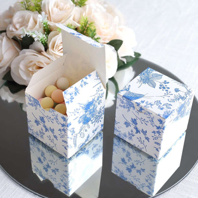 Blue floral gift boxes with decorative eggs on a mirrored surface.