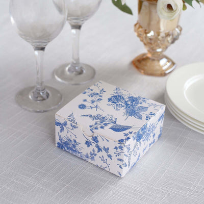 Blue floral gift box on a table with glassware and plates.