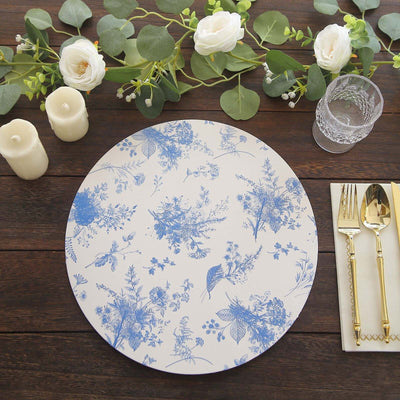 Floral design round placemat on a rustic wooden table with candles and cutlery.
