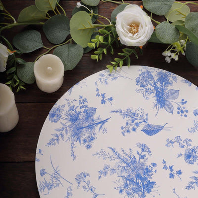 Floral patterned plate on a wooden surface with candles and greenery decorations.