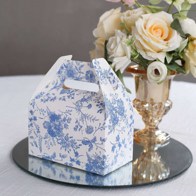 Floral-patterned gift box on a mirrored surface with a vase of roses.