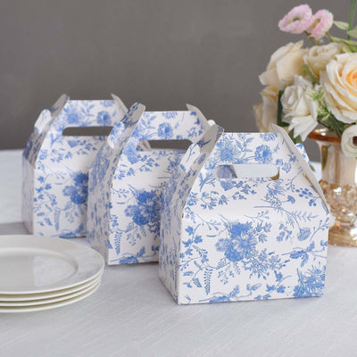 Floral patterned takeout boxes on a table with plates and flowers.