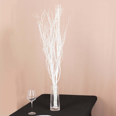 White decorative branches in a glass vase on a black table.