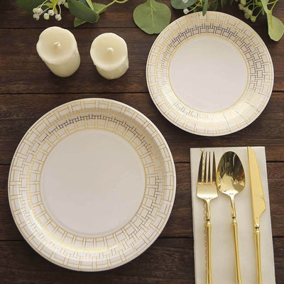 Elegant gold-trimmed dinnerware set with candles on a rustic wooden table.