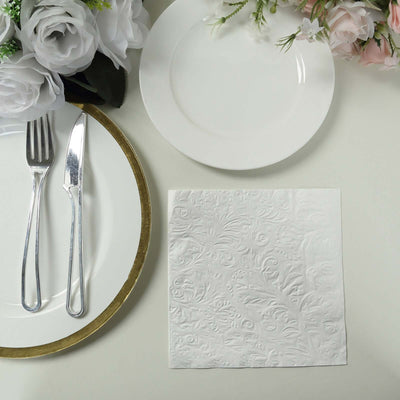 Elegant white embossed napkin on a dining table setting with plates and cutlery.