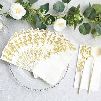 Gold floral napkins with utensils on a table setting.