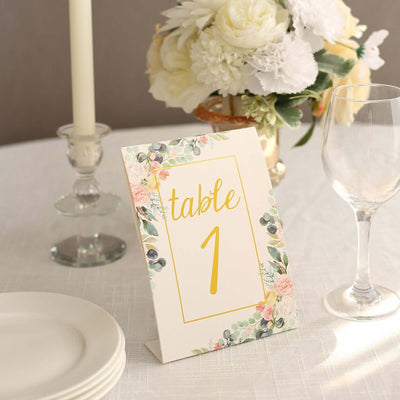 Floral table number sign with yellow text on a decorated table setting.