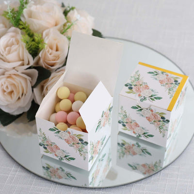Floral gift boxes with pastel candies on a mirrored surface.
