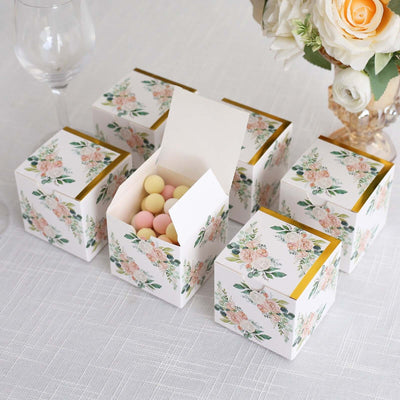 Floral gift boxes with colorful candies inside on a table setting.