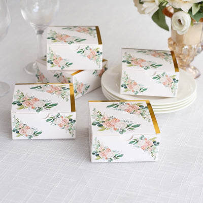 Floral gift boxes with gold accents on a table setting.