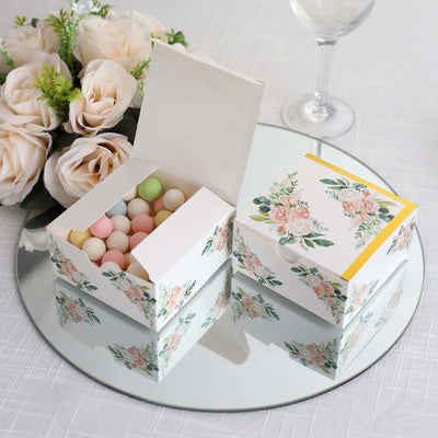 Floral gift box with pastel candies, elegantly displayed on a mirrored surface.