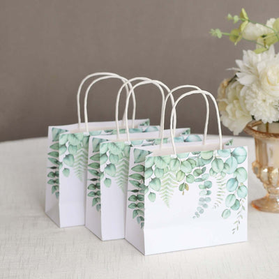 Three decorative gift bags with green botanical designs on a neutral background.
