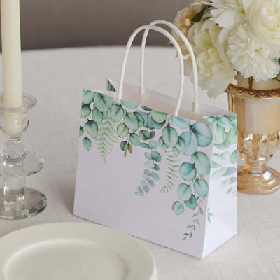 Floral design gift bag on a table with candles and flowers.