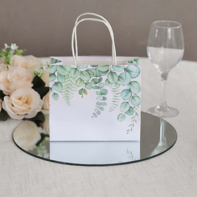 Decorative gift bag with greenery design on a mirror surface.