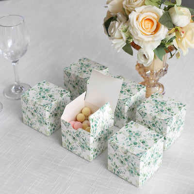 Decorative floral gift boxes with pastel candies on a table.