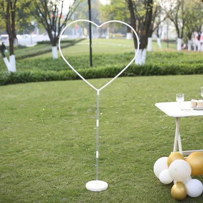 White heart-shaped photo backdrop stand in an outdoor setting.