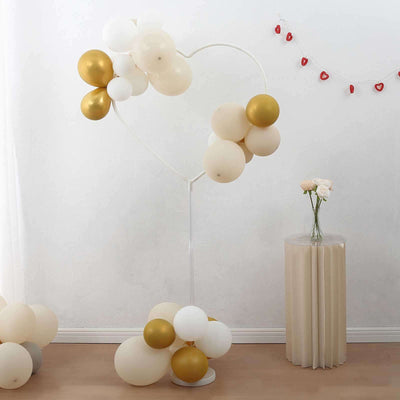 Heart-shaped balloon display with gold and white balloons in a decorated room.
