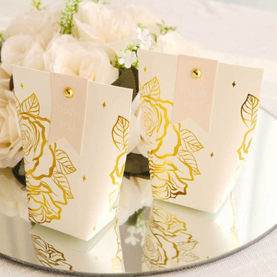 Gold-foiled thank you gift boxes with floral design on a mirrored surface.