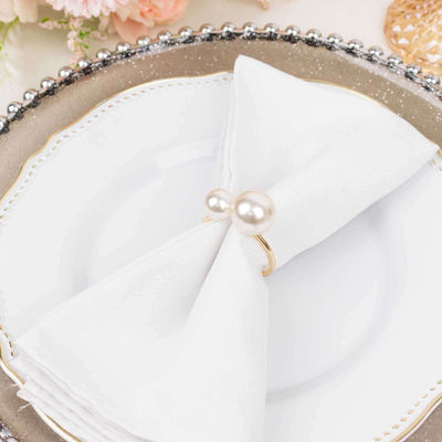 Elegant white napkin with pearl napkin ring on a decorative plate.