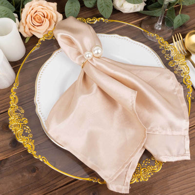 Elegant beige satin napkin with pearl ring on decorative plate.