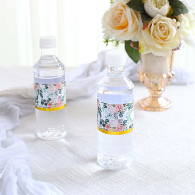 Floral labeled water bottles on a table with a bouquet of roses.