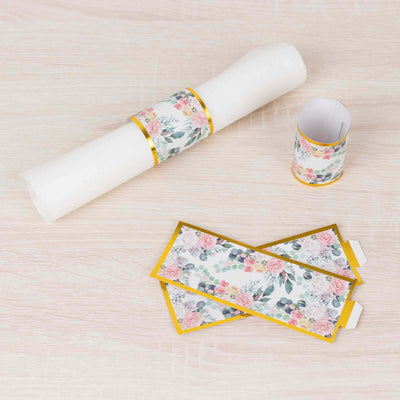 Floral-themed party decorations including scrolls and tags on a light wood surface.