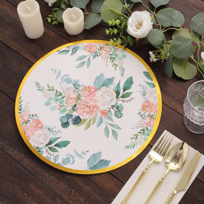 Floral decorative plate with gold trim, surrounded by greenery and candles.