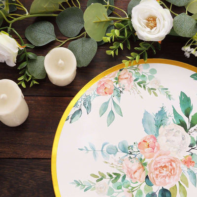 Floral table centerpiece with candles on a wooden surface.