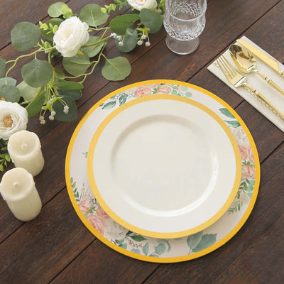 Elegant floral dinnerware set with gold accents and greenery on a wooden table.