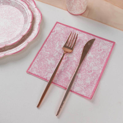 Pink floral napkin with a fork and knife on a white table setting.