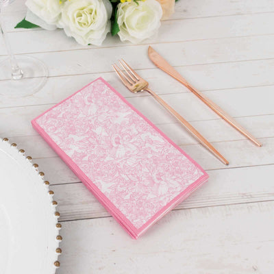 Pink floral-patterned napkins with rose gold cutlery on a wooden table setting.