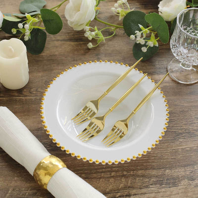 Elegant white plate with gold beaded rim and three gold forks, styled for dining.