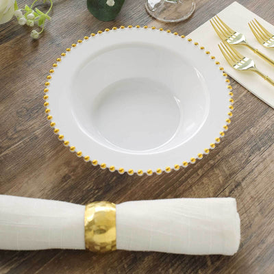 Elegant white bowl with gold beaded rim on a wooden table setting.
