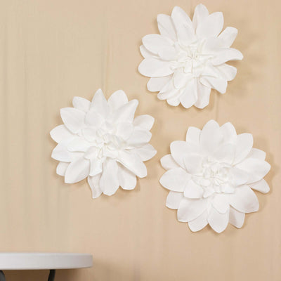 Three white fabric flower wall decor pieces on a beige background.