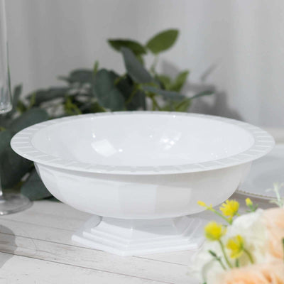 White decorative bowl on a table with greenery and flowers.
