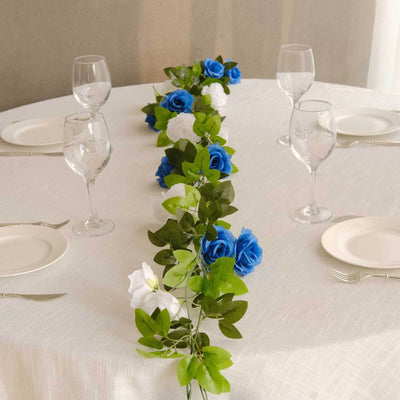 Elegant table setting with blue and white rose garland, wine glasses, and plates.