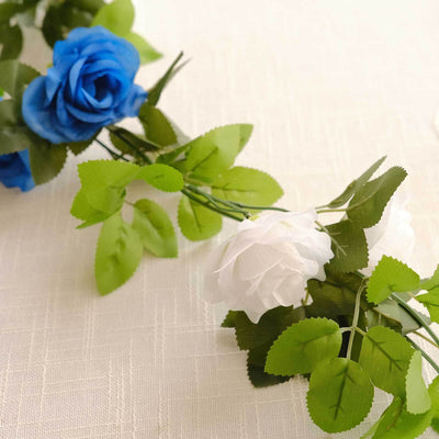 Artificial flower garland with blue and white roses and green leaves.
