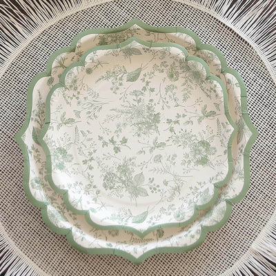 Decorative green and white floral plates stacked on a woven placemat.