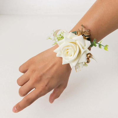 White rose wrist corsage with greenery and decorative accents.