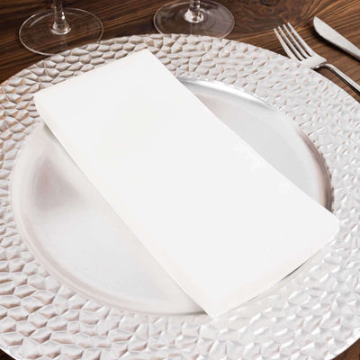 Elegant white napkin on a textured silver charger plate.