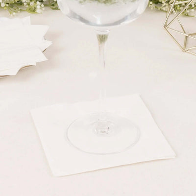 Clear glass wine glass on white napkin, with decorative elements in the background.