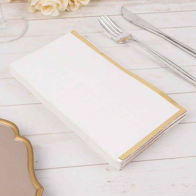 White napkin with gold trim on a wooden table setting.
