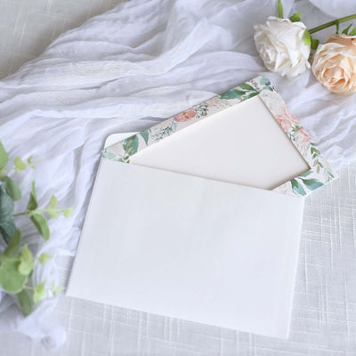 Floral-themed envelope with blank insert on soft fabric backdrop.