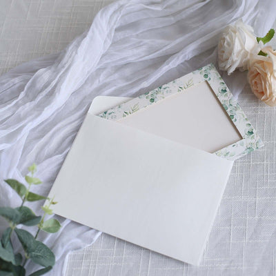 Floral-bordered envelope with blank stationery, styled with soft fabric and flowers.