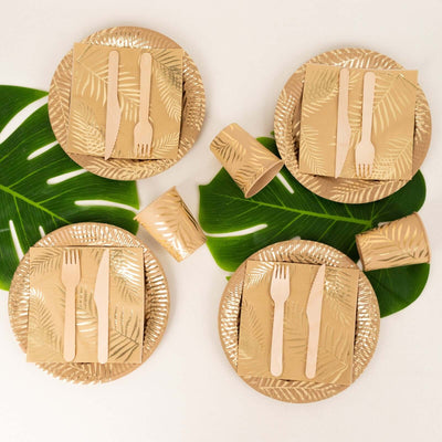 Gold leaf-themed disposable dinnerware set on tropical leaves.